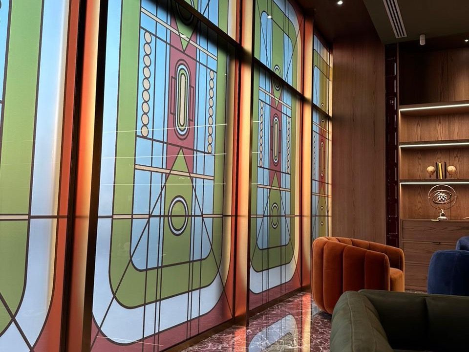 Backlit glass panels printed with an Art Deco geometric pattern in a wood-panelled executive office
