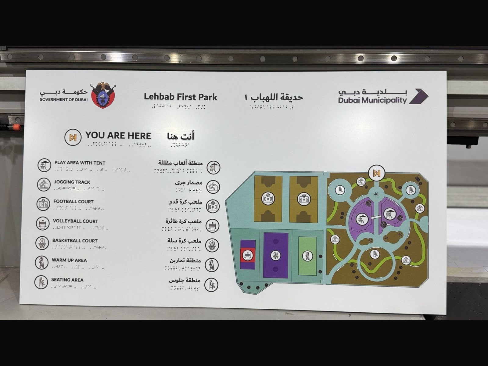 Bilingual Dubai Municipality park sign with raised braille, on the press