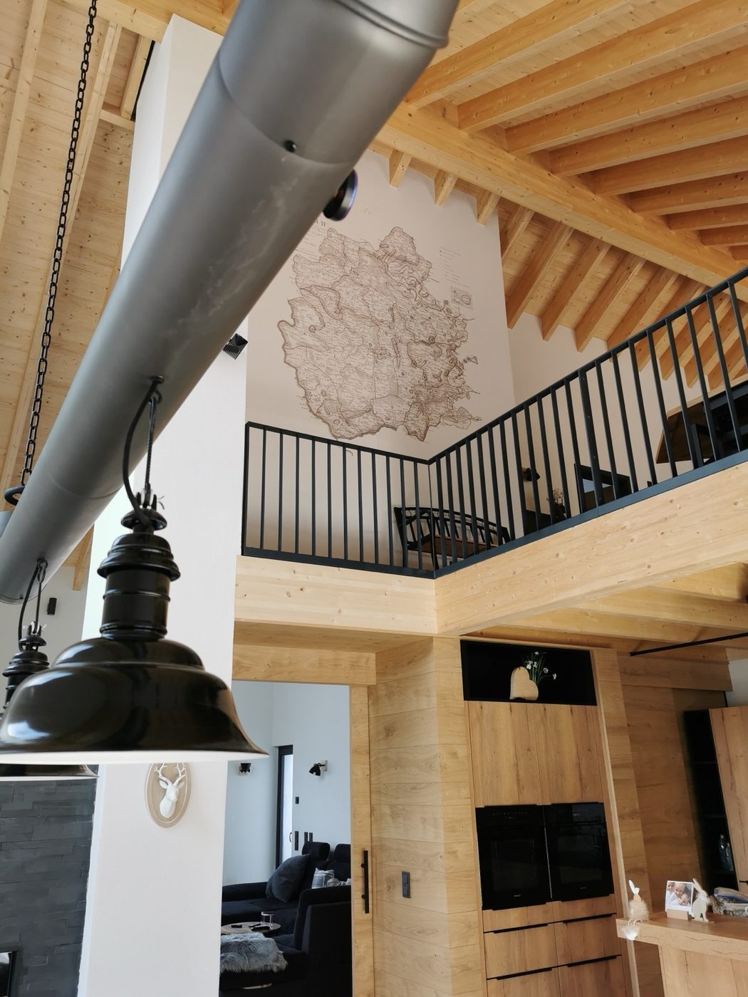 A sepia antique map printed onto a double-height wall in a timber-beamed chalet interior