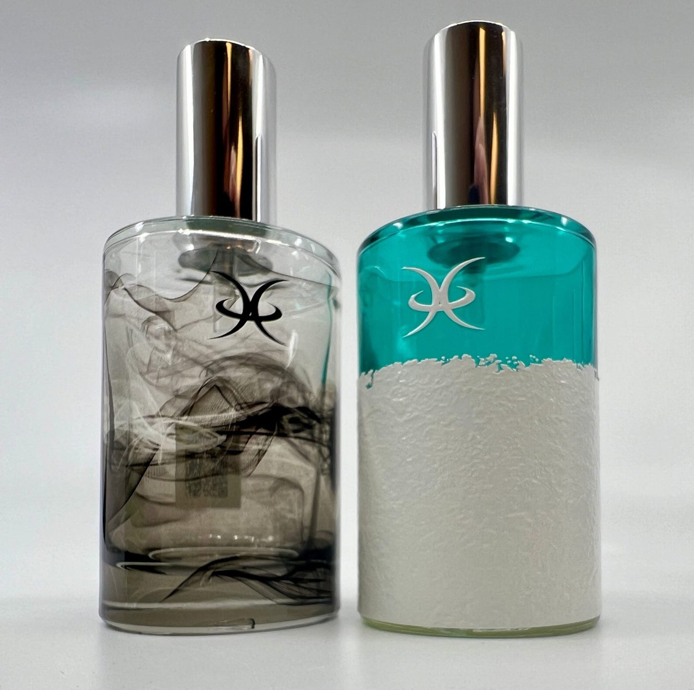Two printed perfume bottles side by side, one with a full photographic wrap and one with a raised textured white finish