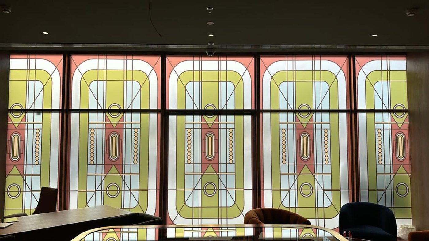 Five window bays glazed with printed Art Deco patterned glass in green, pink and blue