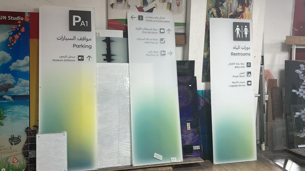 Parking, tickets and restroom wayfinding panels with raised bilingual lettering, in the workshop