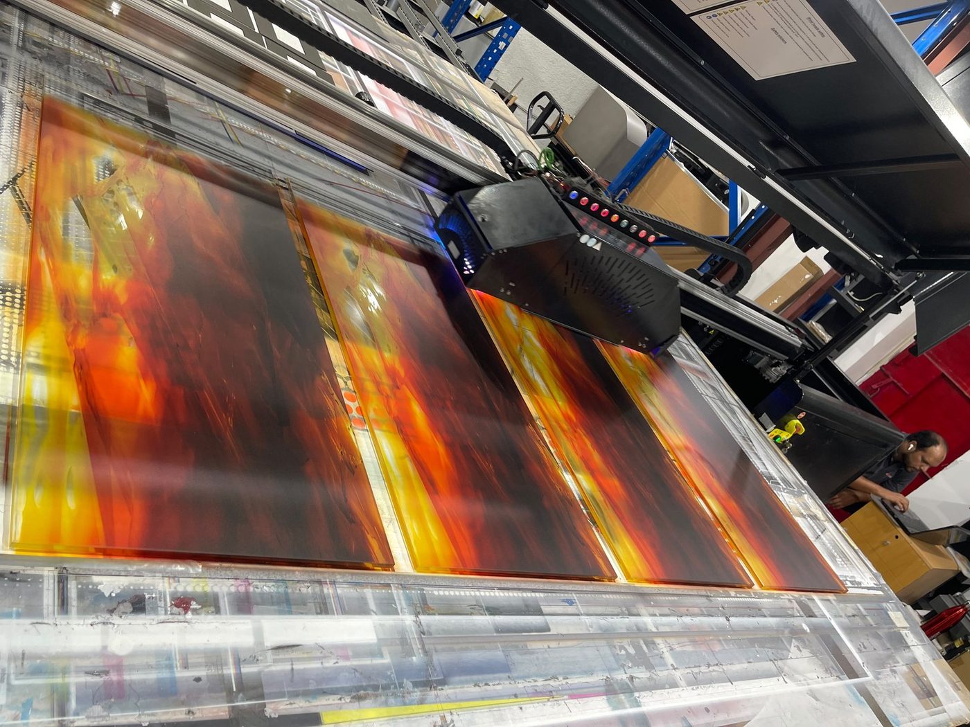A UV flatbed printing four large glass panels at Sun Studio Dubai, the curing lamp travelling across the bed mid-pass