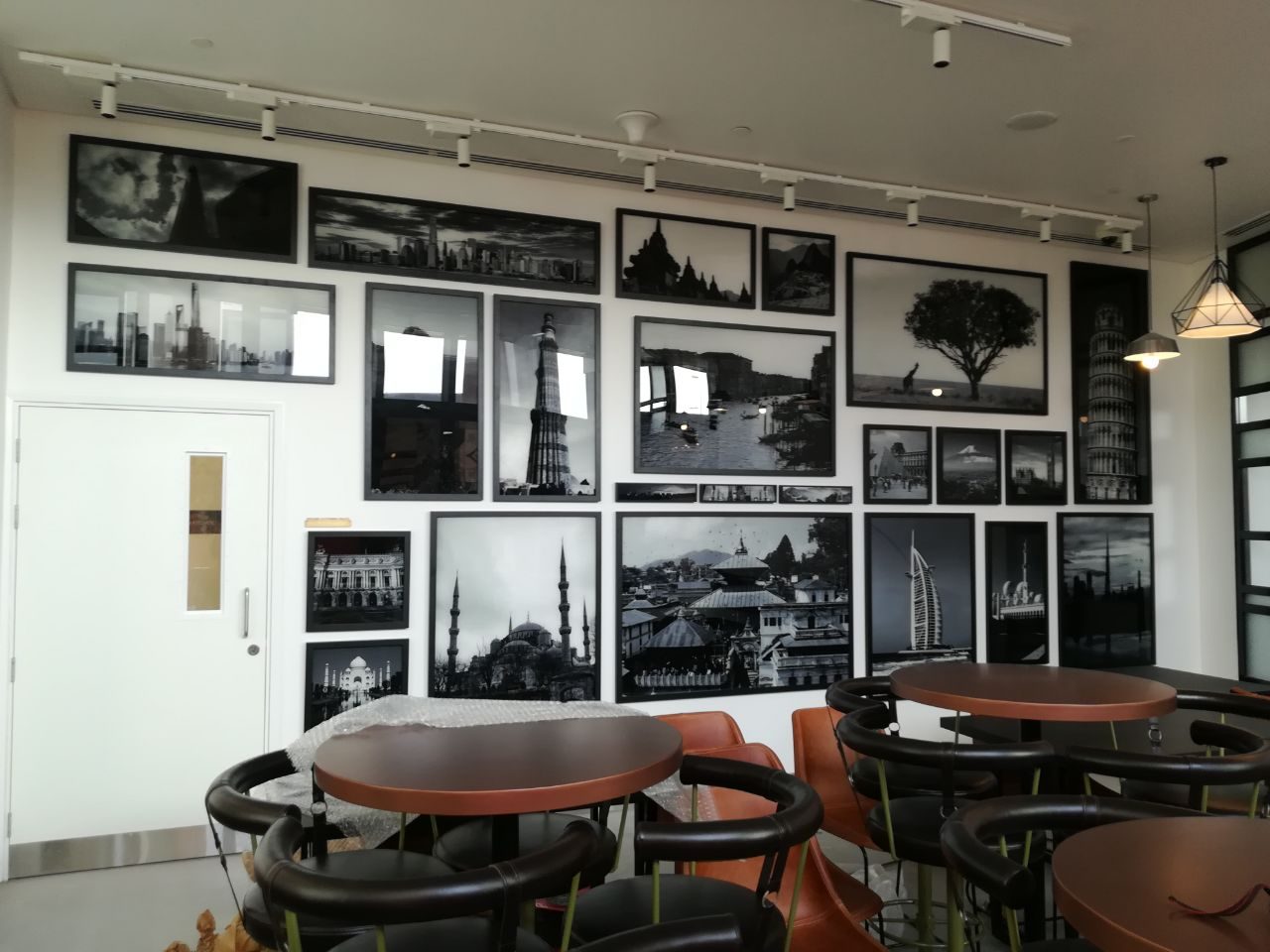 A wall of printed black and white cityscape panels installed in a cafe interior
