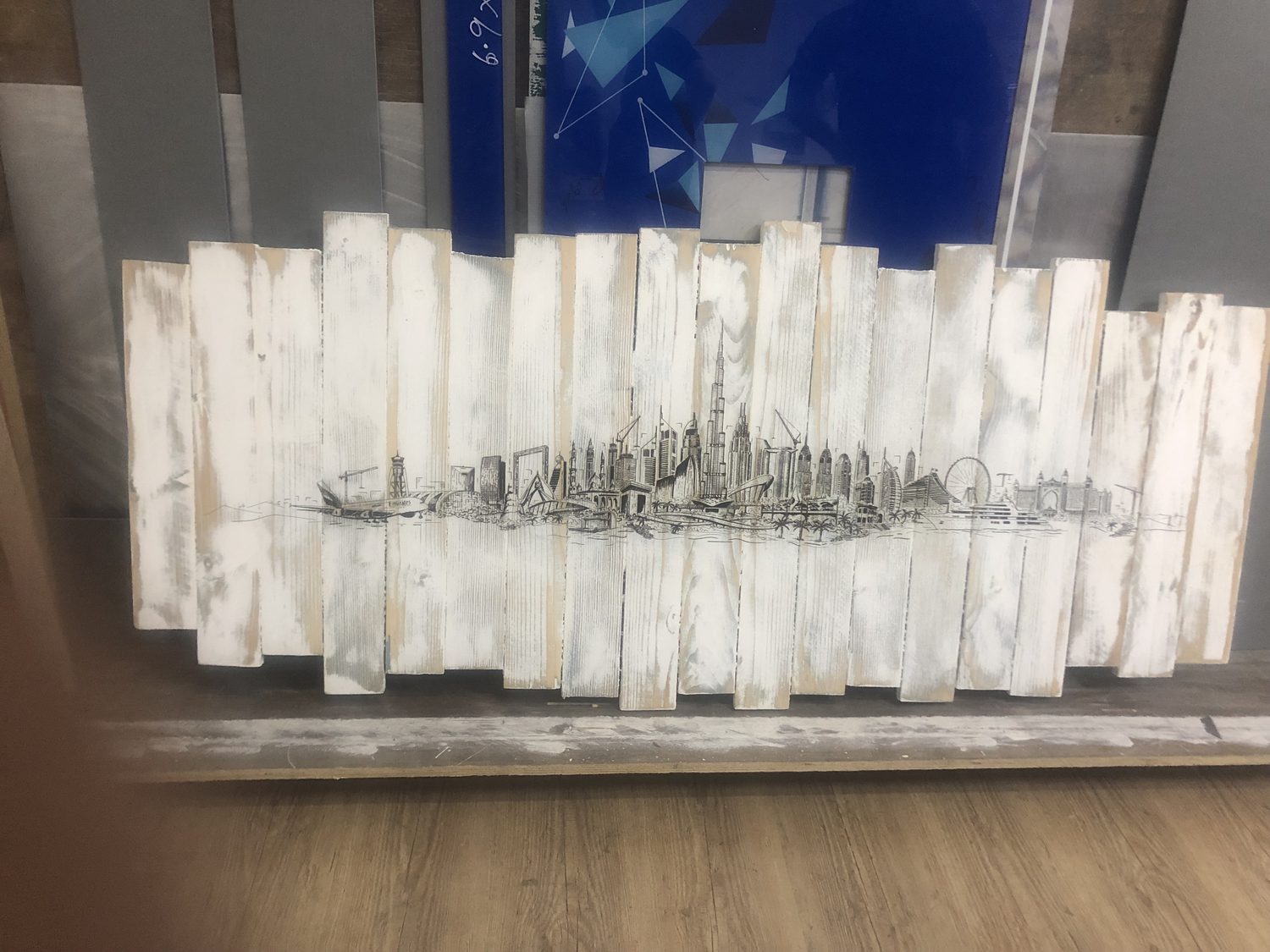 A black line drawing of the Dubai skyline printed across staggered whitewashed timber planks
